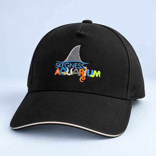 Black baseball cap embroidered with a shark fin above the Skegness Aquarium logo